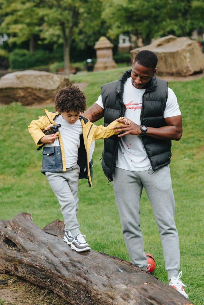 Find your balance. Father helping his son walk on a log.